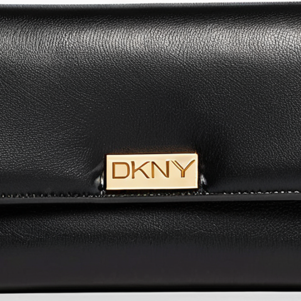 A luxurious and elegant close-up of a DKNY travel wallet and card holder in classic black. The image emphasizes the sleek design, meticulous stitching along the edges, and a subtly shimmering gold or silver metal DKNY logo. The material has a smooth, high-quality leather-like texture, suggesting a soft touch and refined craftsmanship. The lighting is soft and sophisticated, highlighting the rich quality of the product, perhaps resting on a dark, opulent surface. The overall impression is one of modern elegance and deep aesthetic appeal, hinting at an artfully designed accessory.